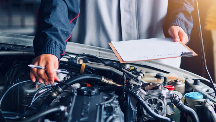 Atelier de réparation automobile avec mécaniciens en salopettes orange travaillant sur véhicules