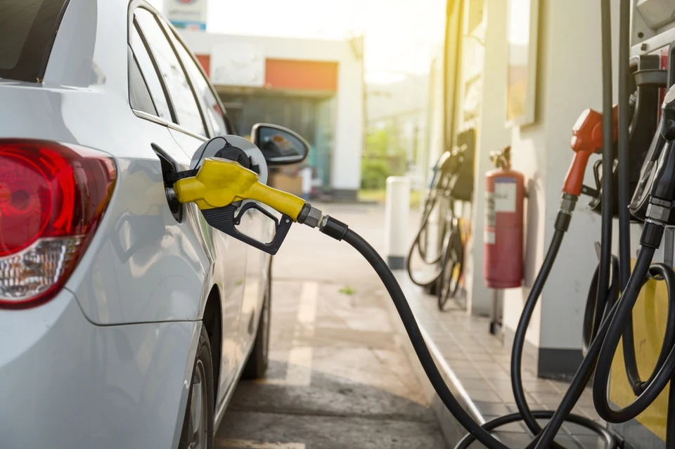 Extérieur, station-service, personne tenant pistolet de distribution de carburant près du réservoir d'un véhicule rouge