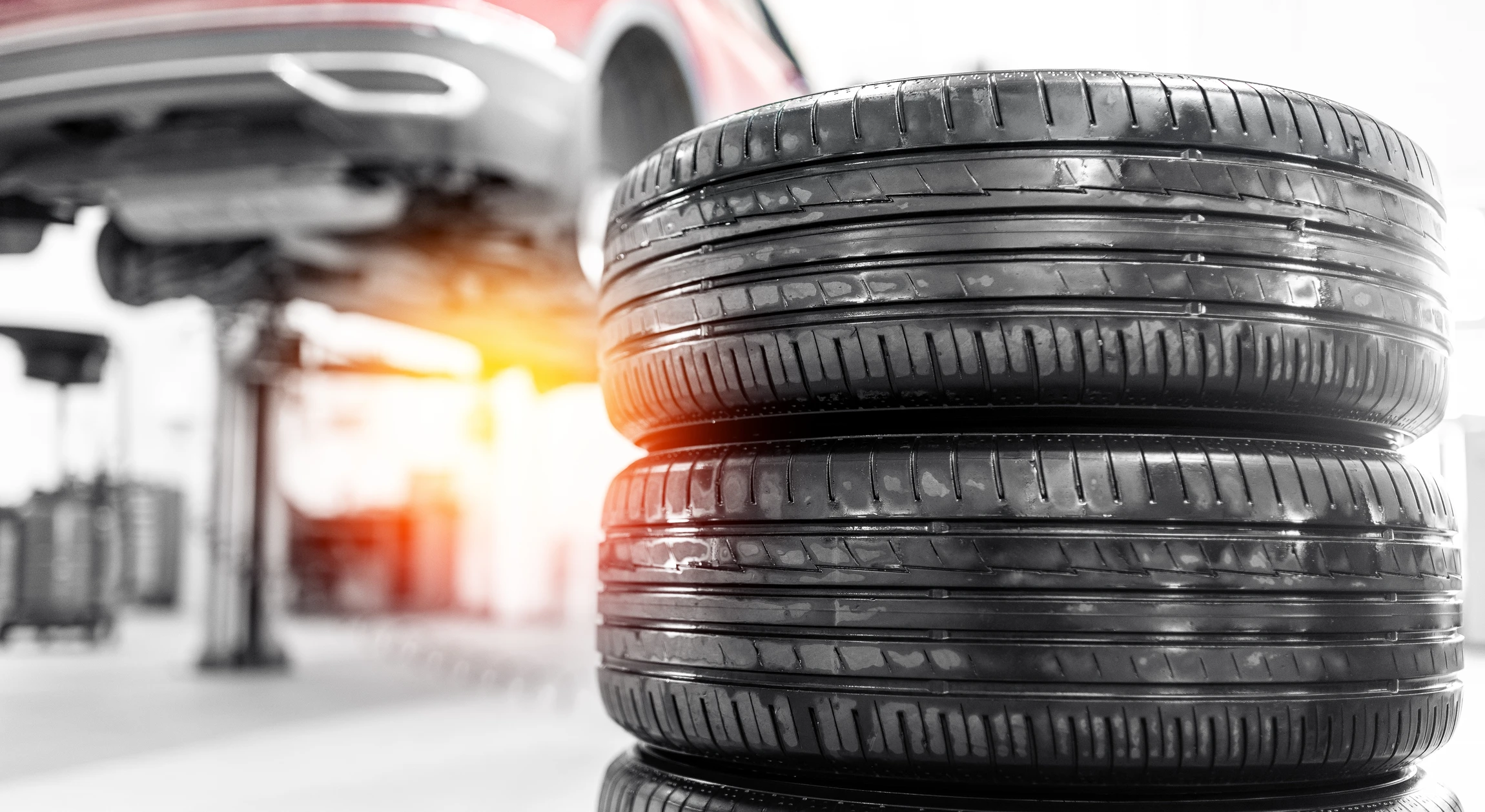 Mécanicien automobile en combinaison bleue effectuant un réglage de géométrie sur roue avant d'un véhicule dans un garage professionnel