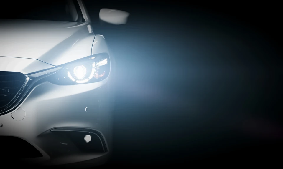 Véhicule de sport noir photographié dans l'obscurité totale, seuls les phares à LED circulaires blancs illuminent la scène frontale