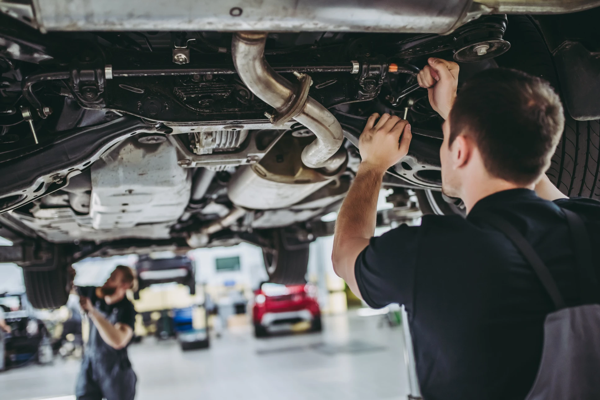 Mécanicien automobile travaillant sous un véhicule surélevé dans un garage professionnel